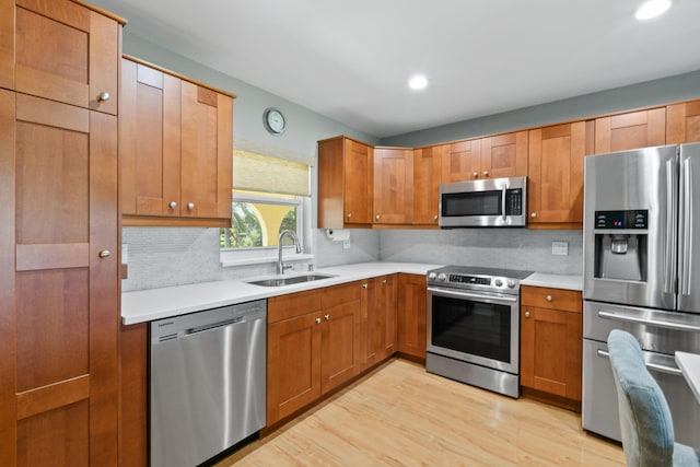 kitchen with sink, appliances with stainless steel finishes, light hardwood / wood-style floors, and tasteful backsplash