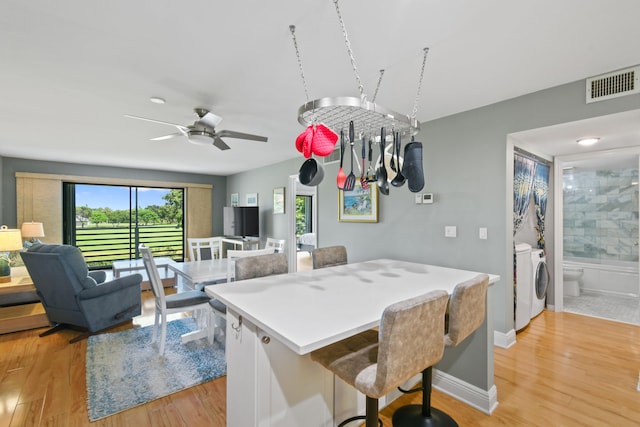 dining area featuring light hardwood / wood-style flooring, washer and dryer, and ceiling fan