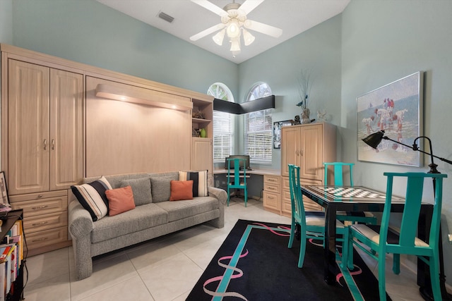 interior space with ceiling fan, light tile patterned flooring, and a high ceiling