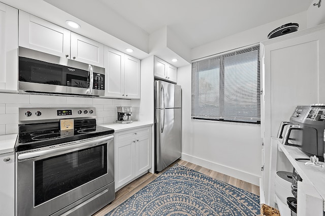 kitchen featuring light hardwood / wood-style floors, stainless steel appliances, tasteful backsplash, and white cabinets