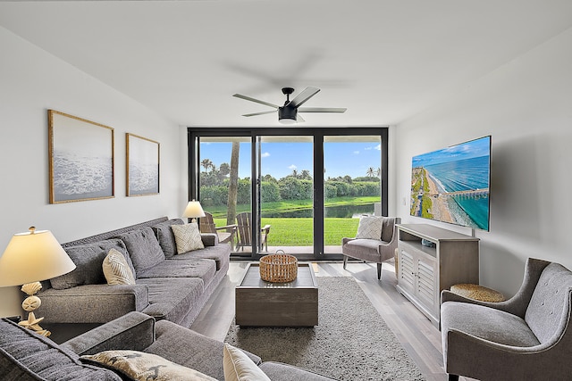 living room featuring light hardwood / wood-style floors, a wall of windows, and ceiling fan