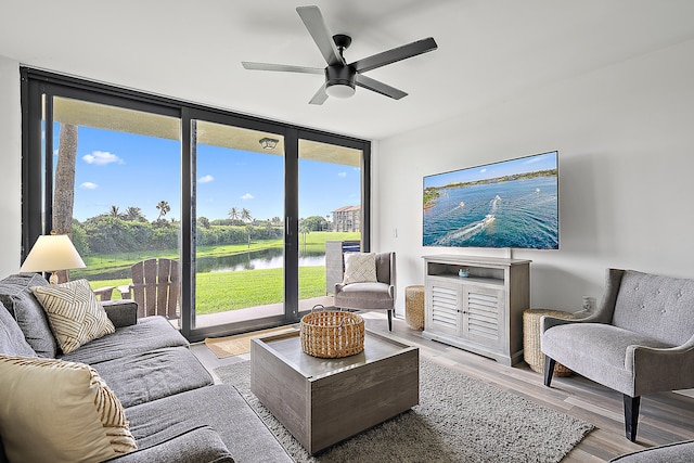 living room with light hardwood / wood-style floors, a healthy amount of sunlight, a wall of windows, and ceiling fan