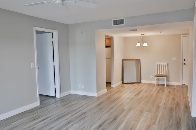 empty room featuring light hardwood / wood-style floors and ceiling fan with notable chandelier