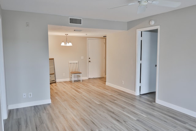 empty room with light hardwood / wood-style flooring and ceiling fan with notable chandelier