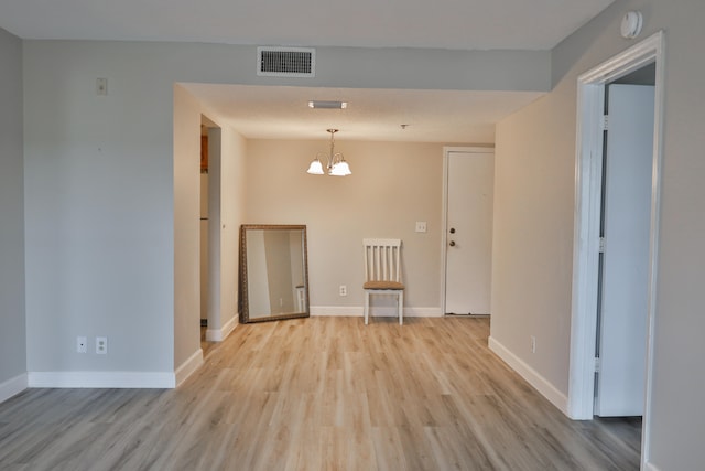 unfurnished room featuring light hardwood / wood-style floors and a chandelier