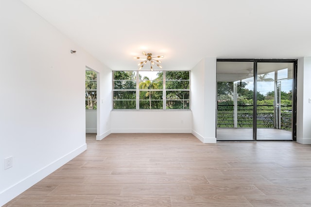 spare room featuring light wood-type flooring and a chandelier