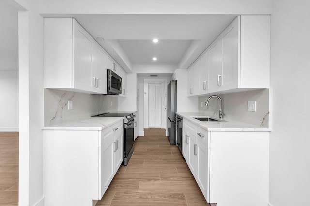 kitchen featuring sink, stainless steel appliances, light hardwood / wood-style flooring, and white cabinets