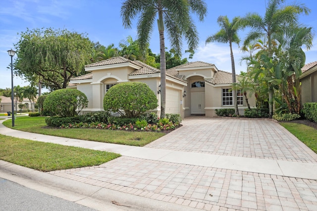 mediterranean / spanish house featuring a garage and a front lawn