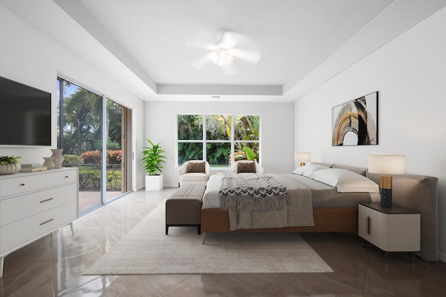 bedroom with ceiling fan, access to exterior, a tray ceiling, and multiple windows