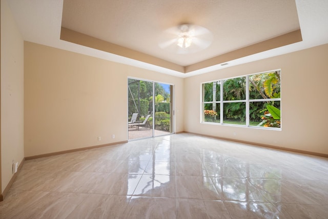 unfurnished room with ceiling fan, a raised ceiling, and a textured ceiling