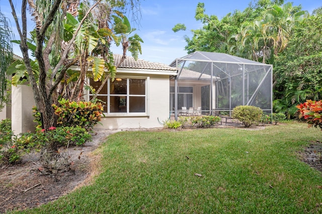 back of house featuring a lawn and glass enclosure