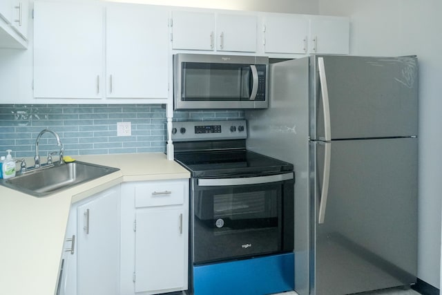 kitchen with sink, tasteful backsplash, white cabinetry, and stainless steel appliances