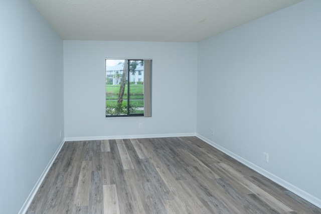 empty room with wood-type flooring and a textured ceiling