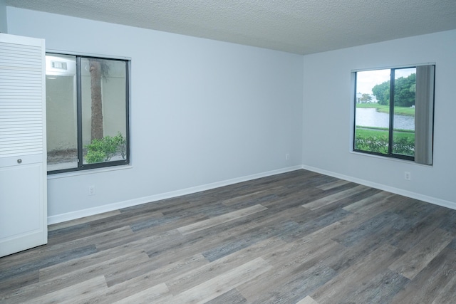 empty room with a textured ceiling and dark hardwood / wood-style floors