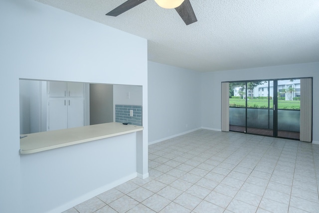 unfurnished room with ceiling fan, light tile patterned floors, and a textured ceiling