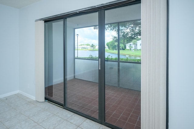 doorway to outside with a water view and light tile patterned floors