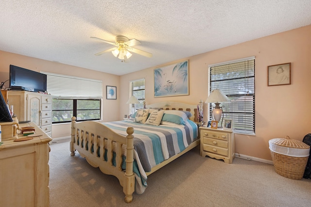 carpeted bedroom with a textured ceiling, baseboards, and a ceiling fan