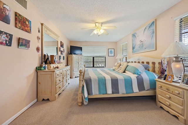 bedroom with light colored carpet, multiple windows, and a textured ceiling