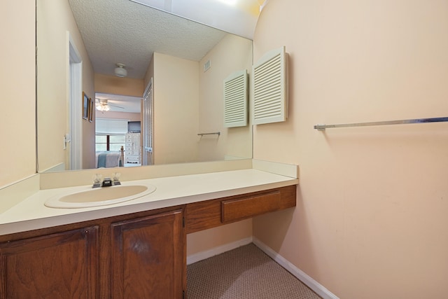 bathroom with a textured ceiling, connected bathroom, visible vents, vanity, and baseboards