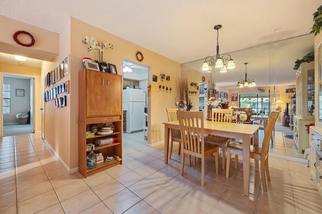 dining space with a textured ceiling, light tile patterned flooring, baseboards, and a notable chandelier