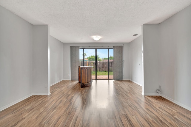 empty room featuring wood-type flooring and a textured ceiling