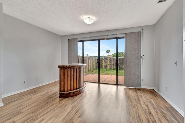 empty room with light hardwood / wood-style floors and a textured ceiling