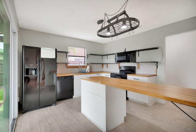 kitchen with white cabinets, wood counters, light hardwood / wood-style flooring, black appliances, and sink