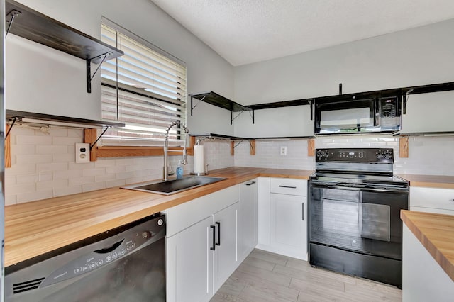 kitchen featuring backsplash, white cabinetry, butcher block counters, black appliances, and sink