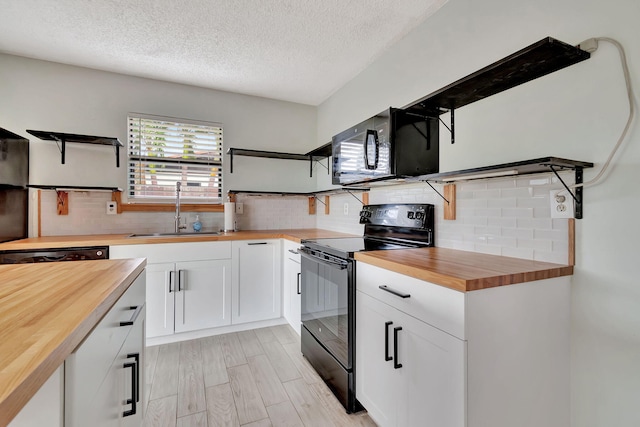 kitchen featuring black appliances, sink, butcher block counters, a textured ceiling, and white cabinetry