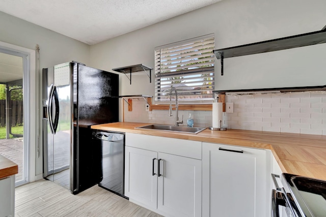 kitchen featuring wooden counters, black appliances, white cabinetry, and plenty of natural light