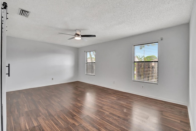 spare room featuring ceiling fan, a textured ceiling, a wealth of natural light, and dark hardwood / wood-style flooring