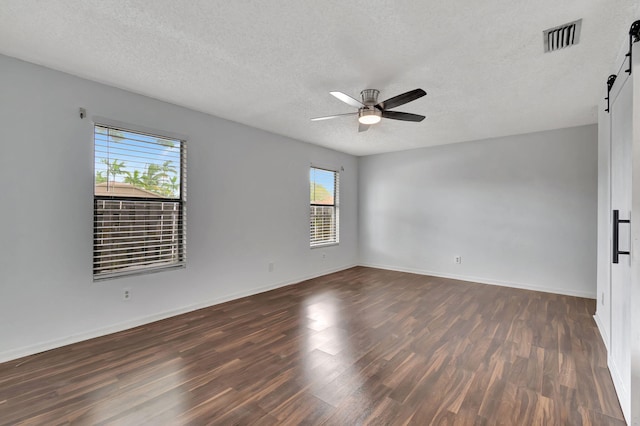 empty room featuring dark hardwood / wood-style floors, a textured ceiling, and a barn door