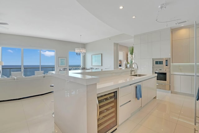 kitchen with wine cooler, a large island with sink, a water view, white cabinets, and appliances with stainless steel finishes