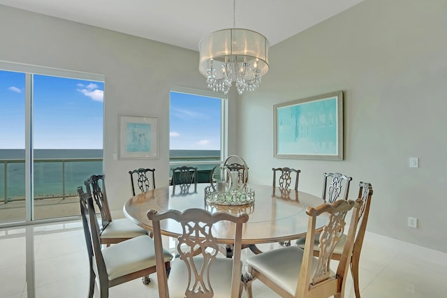 dining area with a water view, light tile patterned floors, and an inviting chandelier