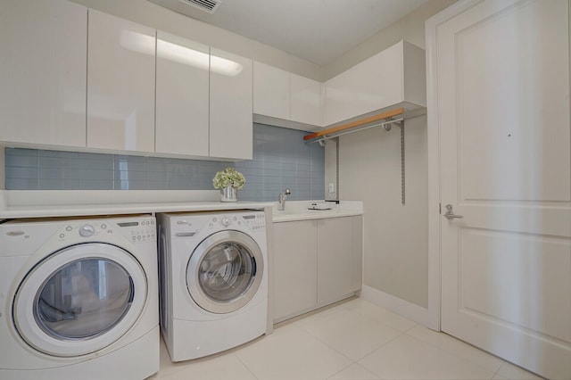 clothes washing area with cabinets, light tile patterned floors, washing machine and dryer, and sink