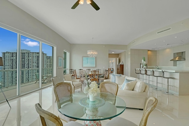 dining space with ceiling fan with notable chandelier and light tile patterned flooring