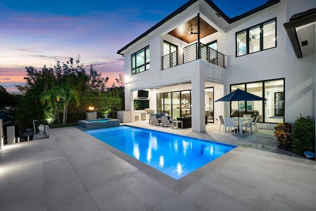 pool at dusk featuring an in ground hot tub and a patio area