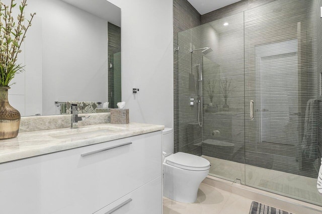 bathroom with toilet, a shower with shower door, vanity, and tile patterned floors