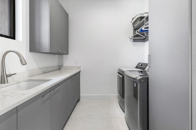 clothes washing area with sink, light tile patterned floors, cabinets, and separate washer and dryer