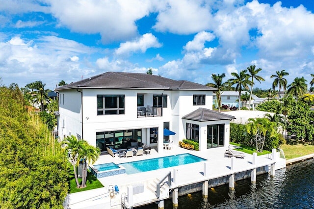 rear view of property with a patio area, a balcony, and a water view