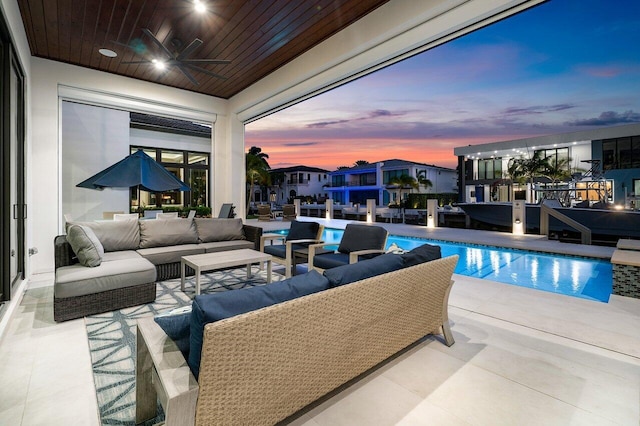 pool at dusk with a patio, an outdoor living space, and ceiling fan