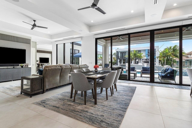 dining room with ceiling fan, a tray ceiling, light tile patterned flooring, and plenty of natural light