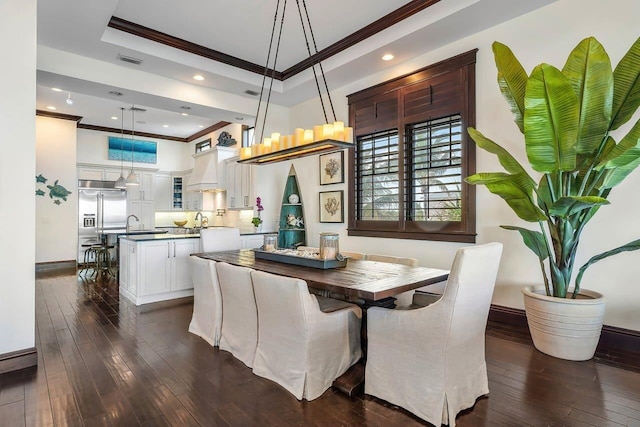 dining space featuring dark hardwood / wood-style flooring, a tray ceiling, crown molding, and sink