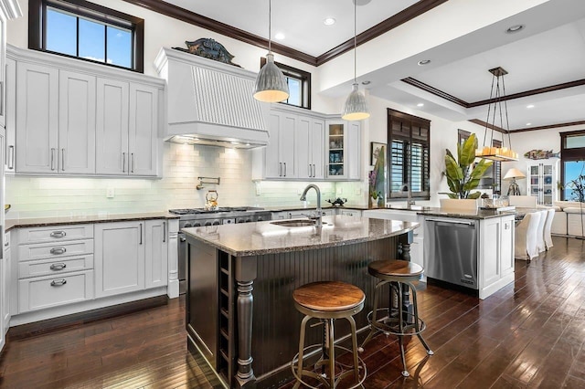 kitchen featuring decorative light fixtures, an island with sink, and dark wood-type flooring