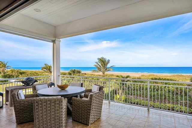 view of patio / terrace featuring a water view, a beach view, and a balcony