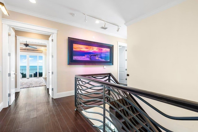 hall featuring dark hardwood / wood-style flooring, a water view, ornamental molding, and track lighting