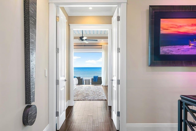 corridor with dark hardwood / wood-style flooring, a water view, and ornamental molding