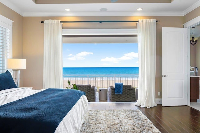 bedroom with crown molding, a water view, a beach view, and hardwood / wood-style flooring