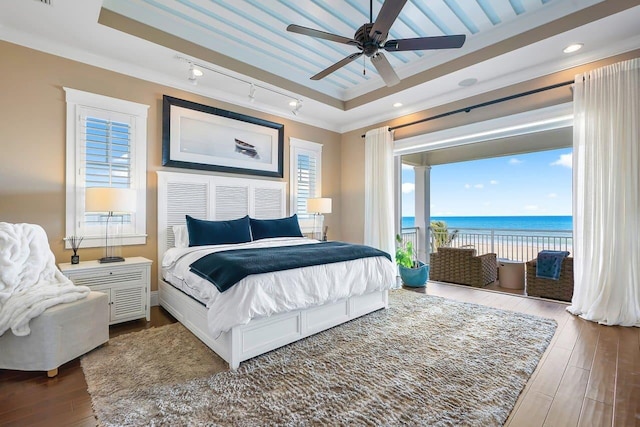 bedroom featuring a water view, multiple windows, and ceiling fan