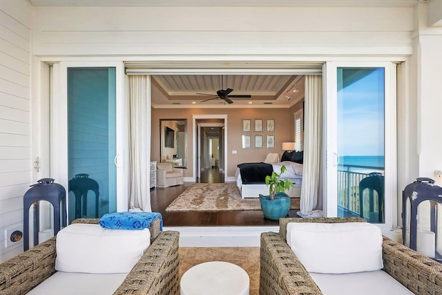 interior space with hardwood / wood-style flooring, ceiling fan, crown molding, and a tray ceiling